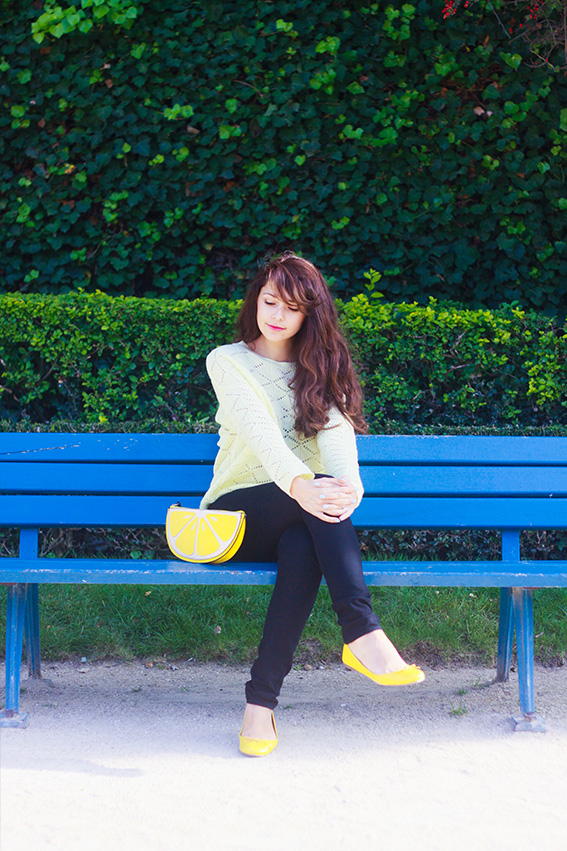 Blogueuse mode française, french fashion blogger. Assise sur un banc, jean slim noir, pull jaune, ballerines jaunes, pochette citron, lemon clutchbag Newlook 